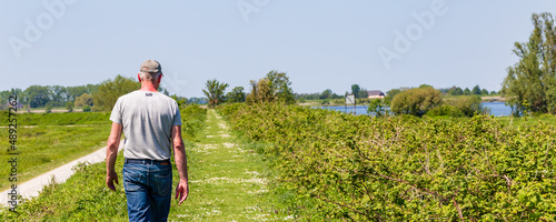 Senior man hiking along a dike at island and nature reserve Tiengemeten Hoeksche Waard n South Holland in The neteherlands photo