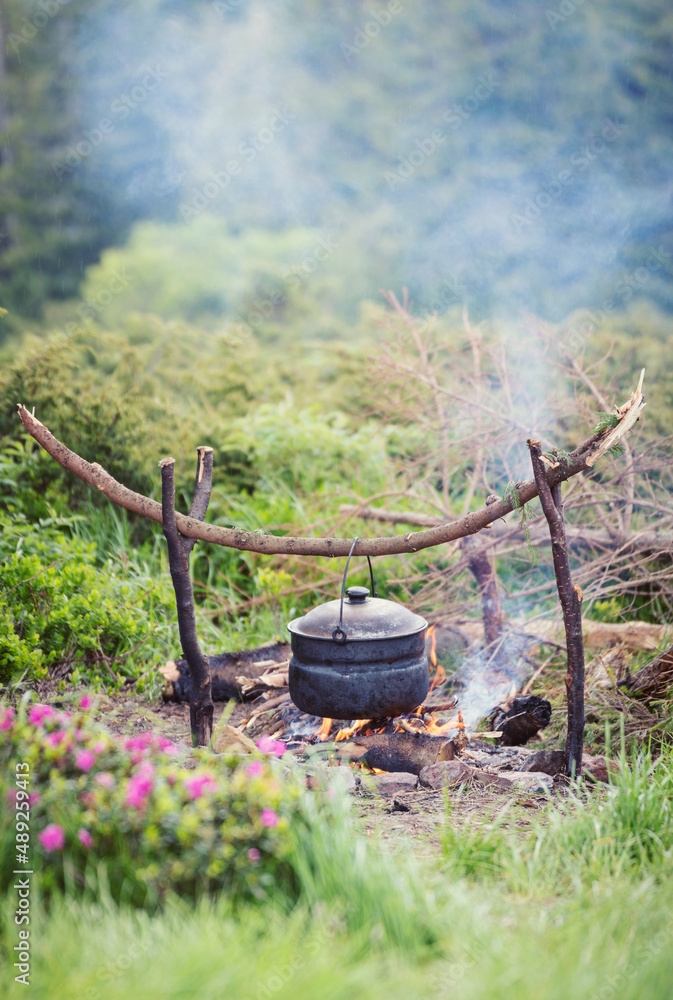 Cooking in field conditions, boiling pot at the campfire Cooking in field conditions, boiling pot at the campfire
