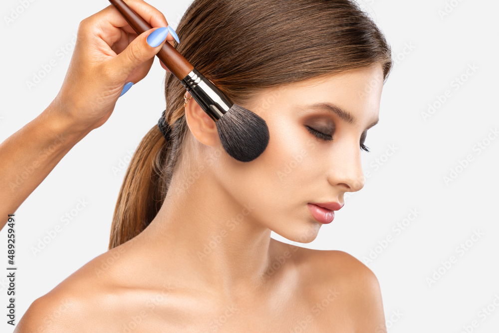 Portrait of a beautiful brunette girl with beautiful fresh makeup and healthy clean skin.Makeup artist holds a powder brush in her hands. Professional makeup concept Portrait of a beautiful brunette girl with beautiful fresh makeup and healthy clean skin.Makeup artist holds a powder brush in her hands. Professional makeup concept