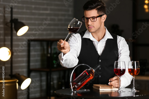 Young male sommelier tastin...