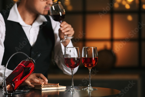 Young male sommelier tastin...
