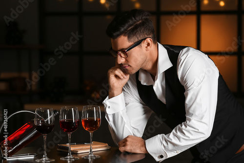 Young male sommelier tastin...