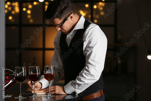 Young male sommelier tastin...