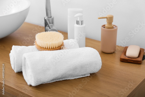 Rolled towels and body brush on table in bathroom