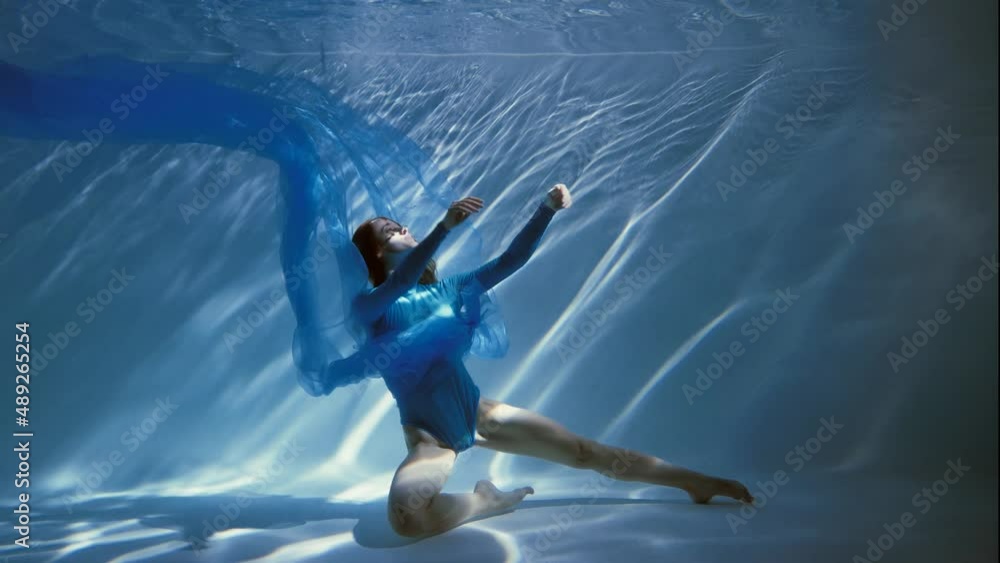 Attractive young woman swims beautifully underwater in a blue dress dress. slow motion Attractive young woman swims beautifully underwater in a blue dress dress. slow motion