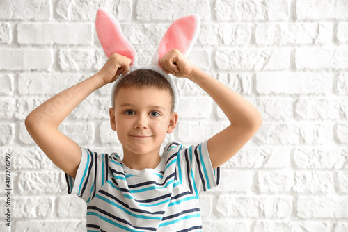 Cute little boy with bunny ears on white brick background