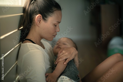 A sad exhausted mother home alone with her baby. Postpartum depression.