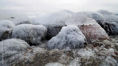 Beautiful icy stones on the winter beach. Wintery rocky beach seascape.