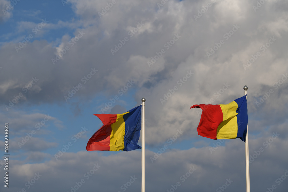 Flag of Romania winding against a spectacular cloudy blue sky Flag of Romania winding against a spectacular cloudy blue sky