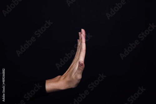 Hand of Caucasian person showing stop sign on black background. Domestic physical and psychological abuse, relative aggression, gaslighting and social injustices. Copy space. photo