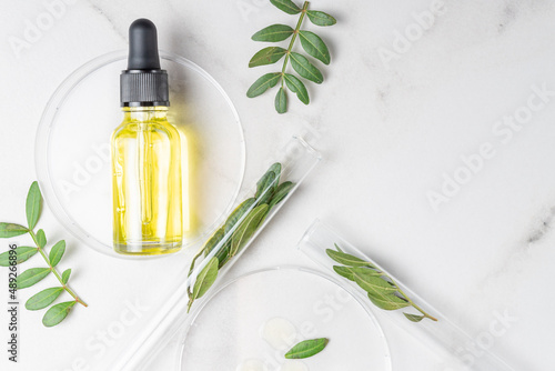 Organic cosmetic product, natural ingredient and laboratory glassware on white marble background, top view. Retynol serum in dropper bottle.