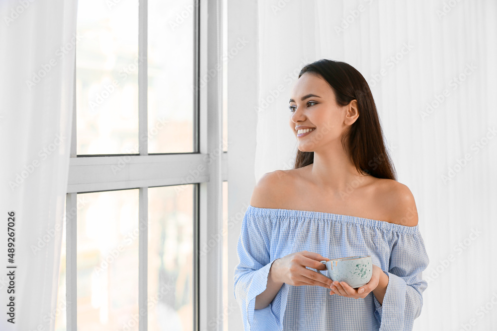 Morning of pretty young woman drinking tea near window Morning of pretty young woman drinking tea near window