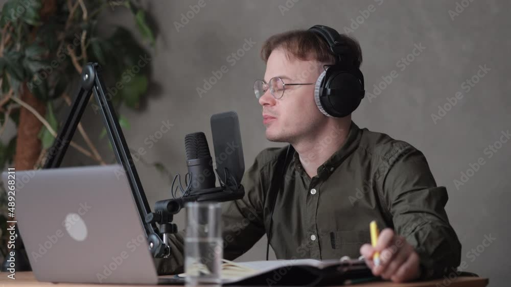 a male radio host or podcaster speaks into a microphone with headphones creates audio content in the studio or on the radio on the air. recording a podcast in a recording studio, a European man in a a male radio host or podcaster speaks into a microphone with headphones creates audio content in the studio or on the radio on the air. recording a podcast in a recording studio, a European man in a