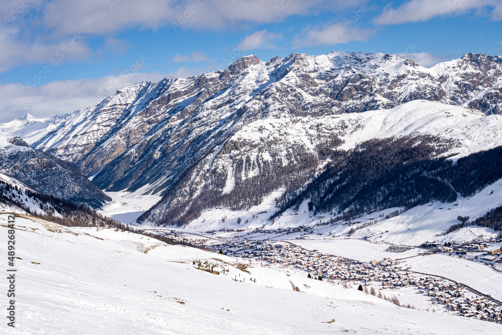 Scenic view of Livigno village in Sondrio province, Italy. Popular skiing resort in European Alps. Snowcapped mountains, houses and ski slopes