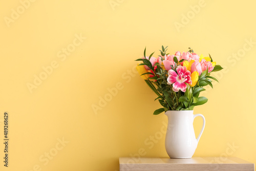 Vase with flowers on table near yellow wall © Pixel-Shot