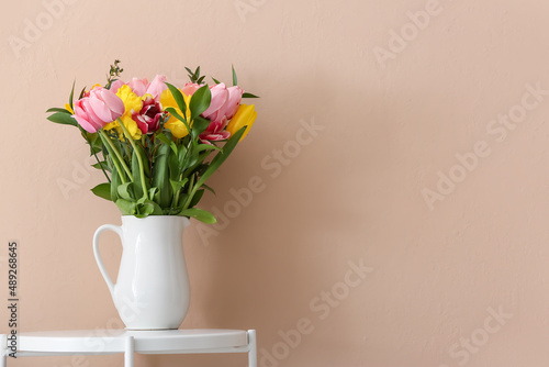 Vase with spring flowers on table near beige wall #489268645
