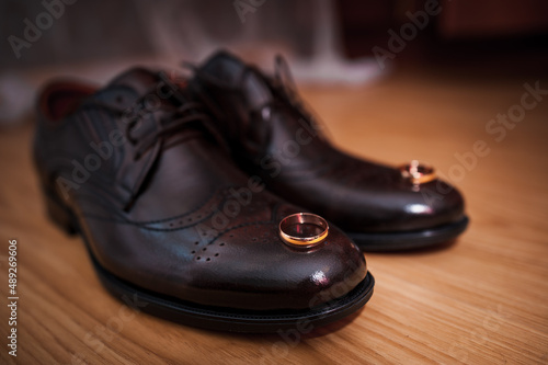 Leather men's shoes, a pair of gold wedding rings in a wooden box. Groom's accessories