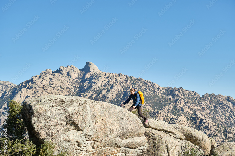 A woman with backpack jumping off a rock in the mountains A woman with backpack jumping off a rock in the mountains