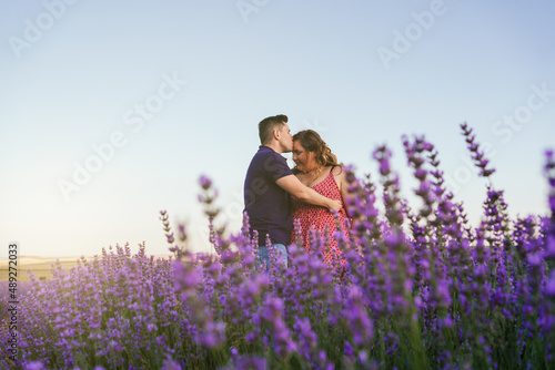 man kissing a plus size woman on the forehead in a lavender field