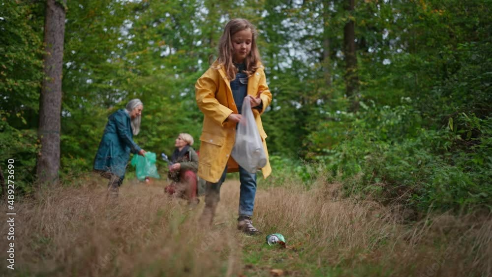 Small girl with mother and grandmother picking up waste outoors in forest. Small girl with mother and grandmother picking up waste outoors in forest.