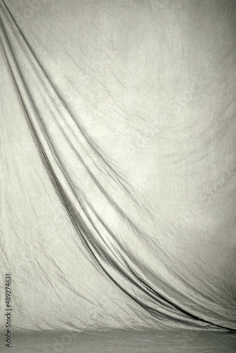 Draped canvas or muslin fabric cloth studio backdrop or background, suitable for use with portraits, products and concepts. Light gray color.