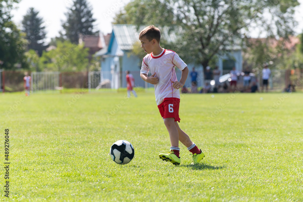 The little football player practicing his football skill alone at the playground. The little football player practicing his football skill alone at the playground.