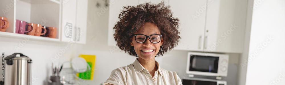 Happy Afro American woman with arms folded standing on office kitchen and looking at camera Happy Afro American woman with arms folded standing on office kitchen and looking at camera