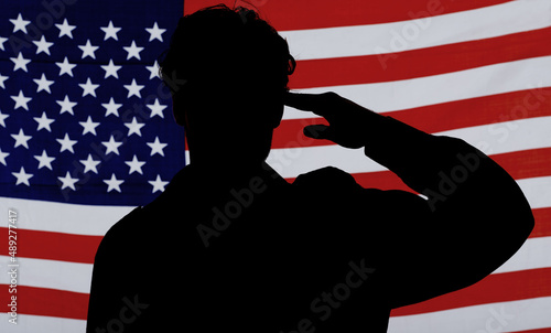 Respect for his country. Silhouette of a soldier saluting against an American flag. photo