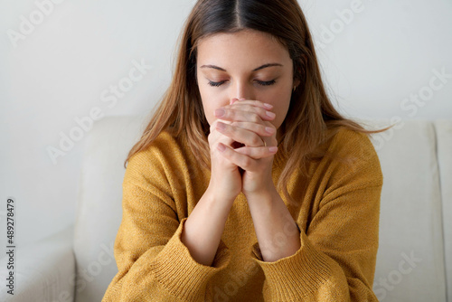 Portrait of worried woman praying at home photo