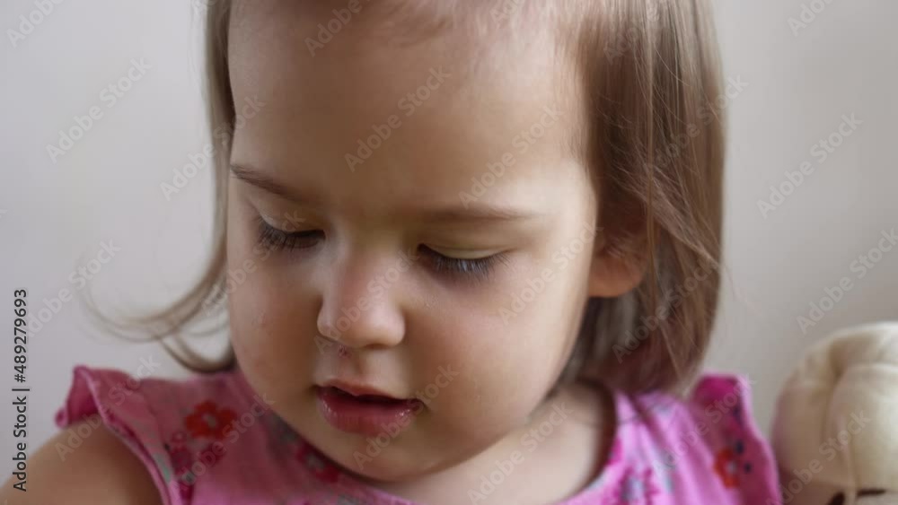 Small Toddler girl Slavic appearance making funny expressive grimace face sticks out tongue at home in room. Childhood emotions feelings sadness happiness. naughty capricious child. Close up kid Small Toddler girl Slavic appearance making funny expressive grimace face sticks out tongue at home in room. Childhood emotions feelings sadness happiness. naughty capricious child. Close up kid