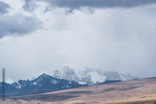 snowy landscape of the mountains in autumn season with yellow vegetation on a sunny day with clouds and blue sky