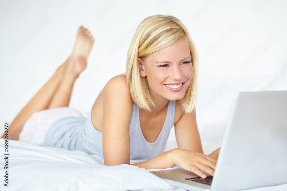 Happily working from home. A young woman working on her laptop from home. Happily working from home. A young woman working on her laptop from home.