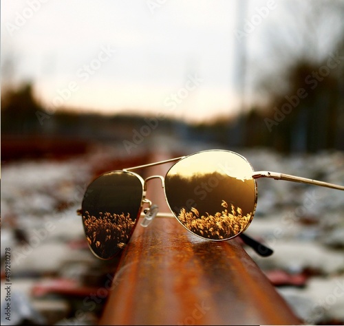 Lunettes sur un rail avec reflet d'un champ avec coucher de soleil.