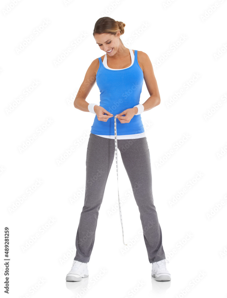 Losing inches and feeling great. Young woman in sportswear measuring her waistline while isolated on white. Losing inches and feeling great. Young woman in sportswear measuring her waistline while isolated on white.