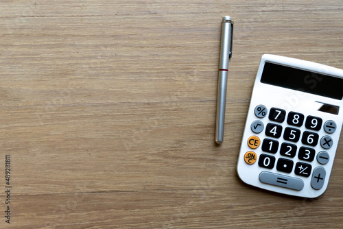 Top table of pen and calculator on wooden surface. Concept for money spending and financial background