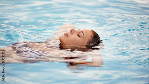 Like floating on a cloud. Cropped shot of a beautiful young woman relaxing in a swimming pool.