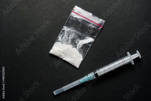 Картината върху платно White powder drugs on ziplock plastic bag and syringe on dark table with empty s