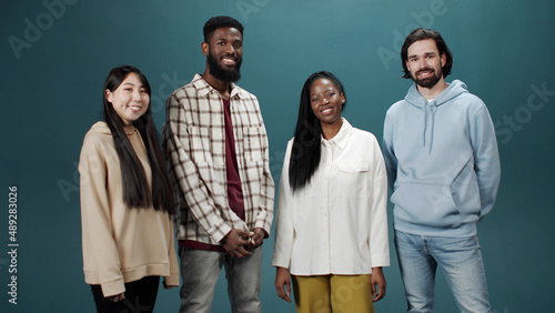 Four happy young people bonding and looking at camera with smile with green background