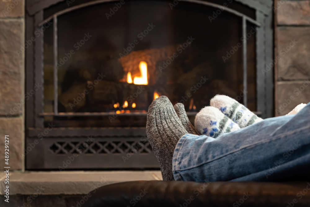Scene of a couple in front of fireplace. They are wearing jeans and warm cozy socks. Intentional defocused background. 