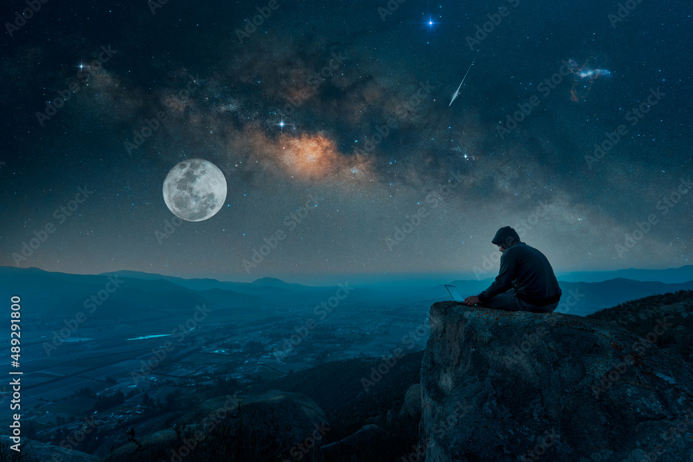 person silhouette with a laptop on the top of the mountain under the starry night - obrazy, fototapety, plakaty 