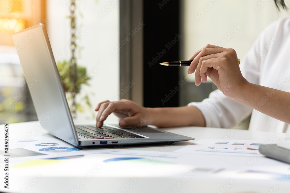 Fototapeta premium A businessman or accountant uses a laptop computer with business documents, diagrams and calculators on his desk. Businessman's hands analyze office finance graph document
