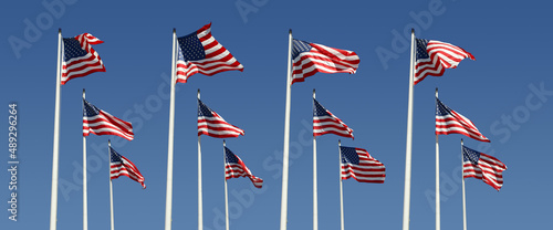 rows of american flags on a bright blue sky