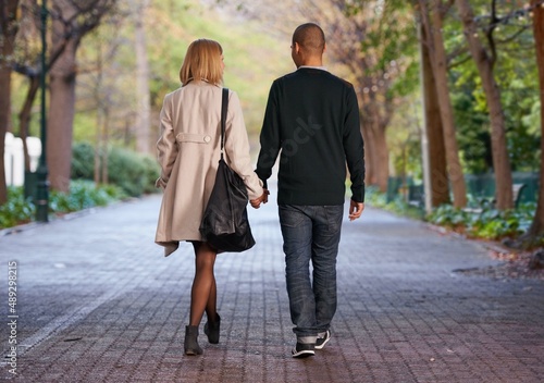This is what love is all about. Full length rearview shot of a young couple walking hand in hand in a park.