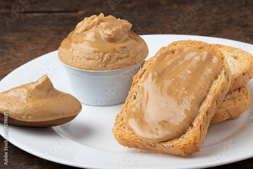 Toasted bread covered with peanut butter on a plate.