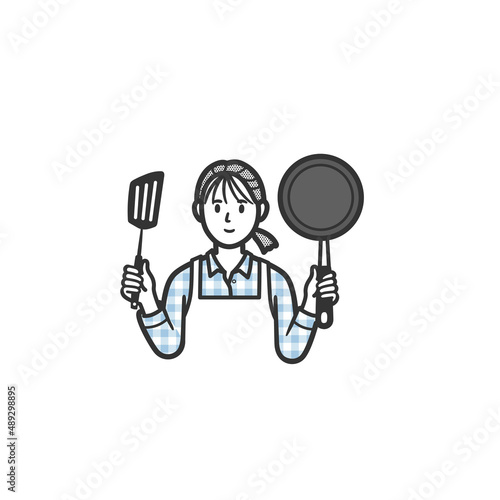 フライパンとフライ返しを持つ主婦