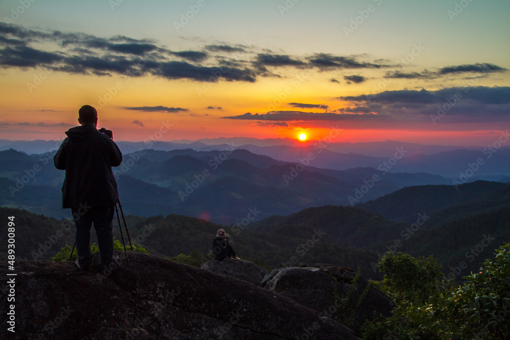 silhouette of a man standing on a mountain top at sunset