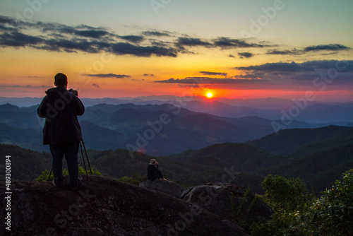 silhouette of a man standing on a mountain top at sunset © Soonthorn