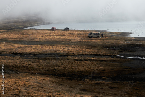 Cars parked on shore of lake in foggy weather
