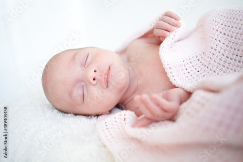 Peaceful sleep. A beautiful infant girl sleeping while wrapped up in a blanket.