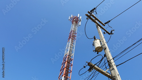 Transformers and telecommunication towers. High voltage system on concrete towers to supply power to 4G and 5G cellular telecommunication towers against a blue sky background. Selective focus